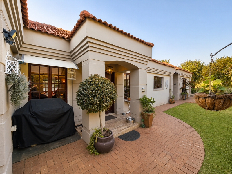 A well-maintained rear patio area featuring brick paving, terracotta roof tiles, and direct access to the garden through timber-framed glass doors.