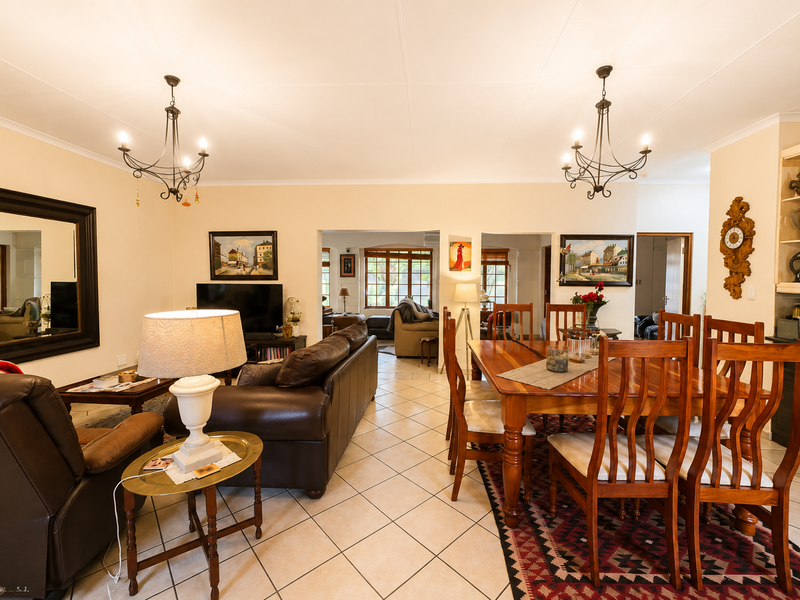 Spacious open-plan living and dining area featuring tiled flooring, classic wrought iron chandeliers, and neutral wall finishes, creating a warm and inviting atmosphere.