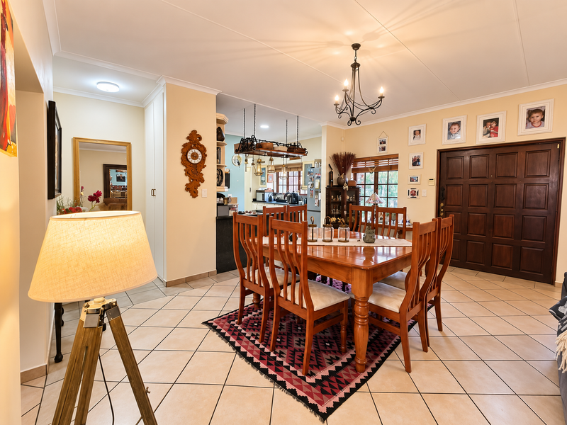 Spacious open-plan dining area featuring tiled floors, a classic chandelier, and direct access to a functional kitchen with built-in cabinetry and a central island.