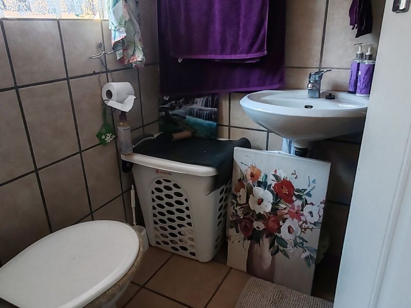 A compact guest bathroom featuring a pedestal basin, toilet, and tiled finishes throughout.