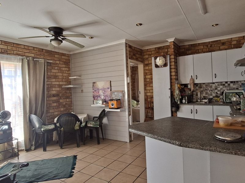 Open-plan living and kitchen area featuring exposed brick walls, tiled flooring, and a functional kitchen with granite countertops and ample cabinetry.