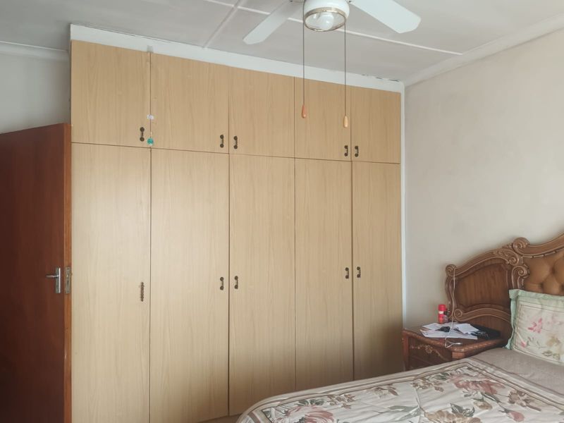 A bedroom featuring floor-to-ceiling built-in wooden cupboards and a ceiling fan, providing ample storage space.