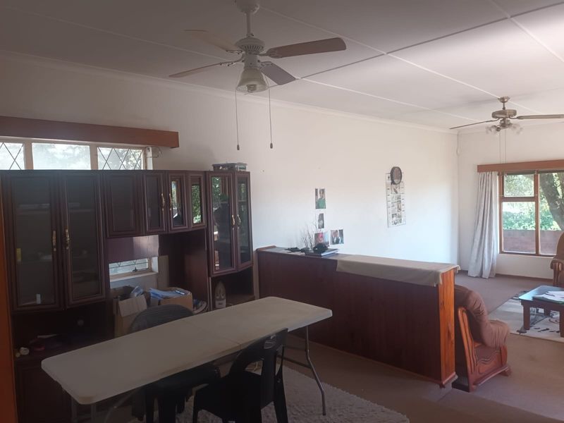 Spacious living area featuring a timber room divider, built-in cabinetry, and ceiling fans, offering a functional layout with potential for modernization.