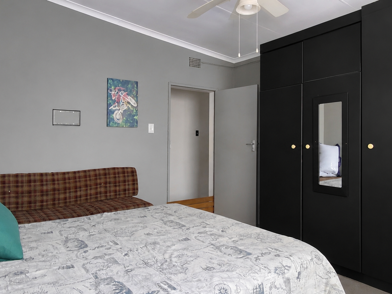 A bedroom featuring a large black built-in wardrobe, a ceiling fan, and neutral wall finishes.
