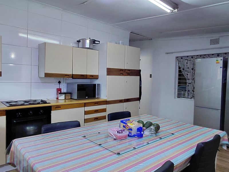 A functional kitchen featuring built-in cabinetry, an electric hob, an oven, and tiled splashbacks, offering a practical layout for daily meal preparation.