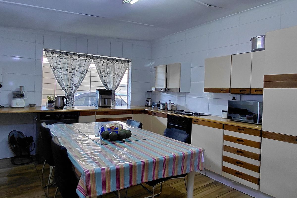 A functional kitchen featuring built-in cabinetry, laminate countertops, and a built-in oven, with tiled walls and security bars on the window.