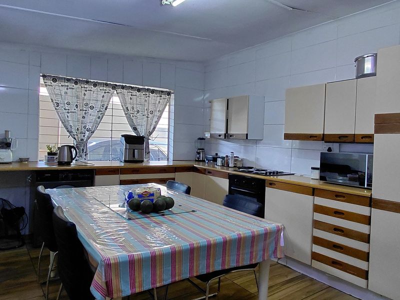 A functional kitchen featuring built-in cabinetry, laminate countertops, and a built-in oven, with tiled walls and security bars on the window.