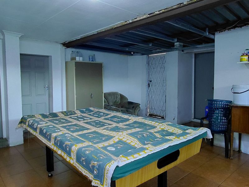 A utility or multi-purpose room featuring tiled flooring, an exposed structural steel beam, and a wood-burning stove, currently used as a recreational space.
