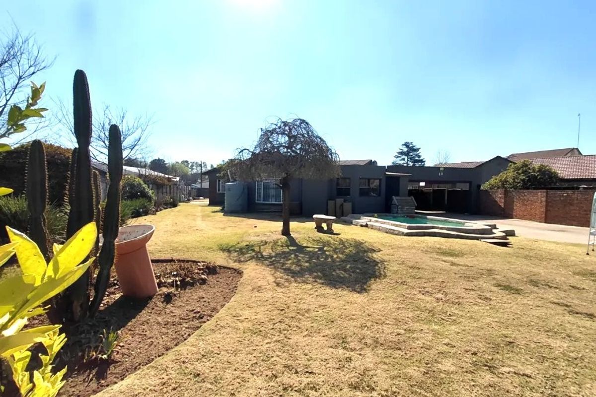 Spacious rear garden featuring a swimming pool, paved surround, and water tank, set against the rear elevation of the house.
