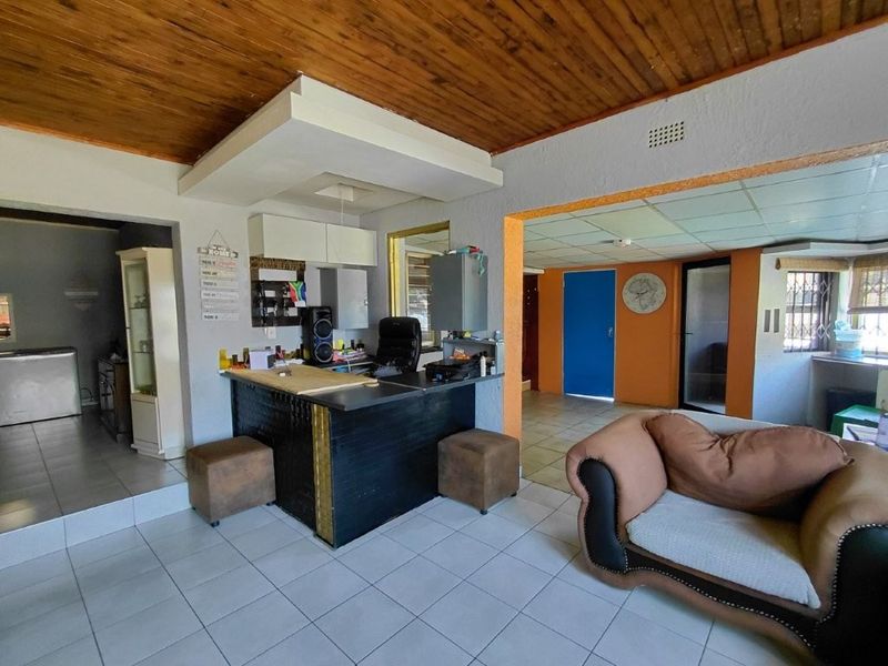 Open plan living area featuring a built-in bar, tiled flooring, and a timber ceiling, offering a versatile space for entertaining.