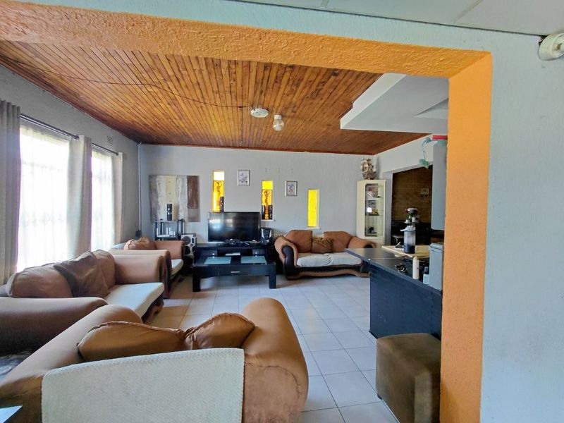 Open plan living area featuring tiled flooring, a timber tongue and groove ceiling, and built-in wall niches, connecting to a kitchen breakfast bar.