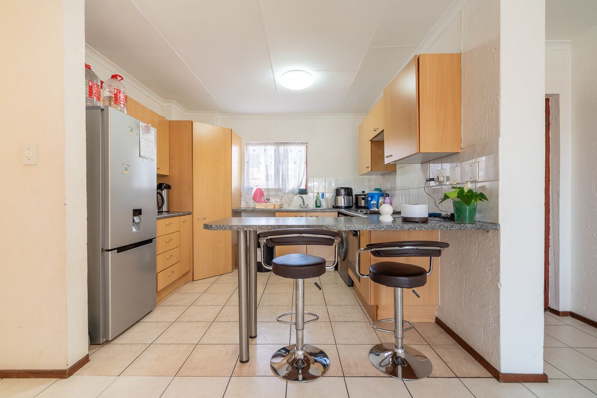 Functional kitchen featuring laminate cabinetry, granite countertops with a breakfast bar, and tiled flooring, offering a practical layout for daily use.