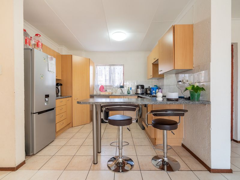 Functional kitchen featuring laminate cabinetry, granite countertops with a breakfast bar, and tiled flooring, offering a practical layout for daily use.
