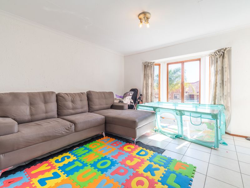 A bright living room featuring tiled flooring, a large bay window allowing natural light, and coved ceiling details.