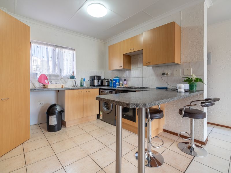 Functional kitchen featuring laminate cabinetry, a breakfast bar, tiled flooring, and built-in cooking appliances, offering a practical layout for daily use.