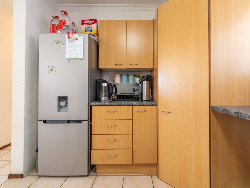 A compact kitchen area featuring light wood-finish cabinetry, granite countertops, and tiled flooring, providing functional storage and workspace.
