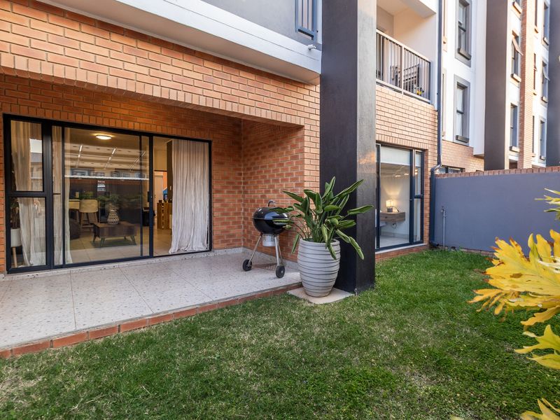 A well-maintained ground floor patio featuring tiled flooring and sliding glass doors, providing seamless access to a private garden area.
