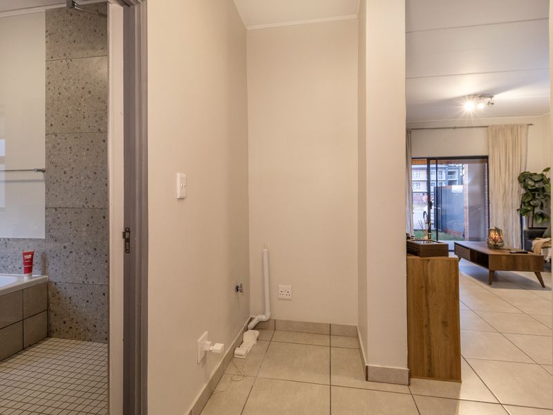 A clean, neutral hallway area featuring tiled flooring and dedicated plumbing and electrical connections, providing a functional transition space between rooms.