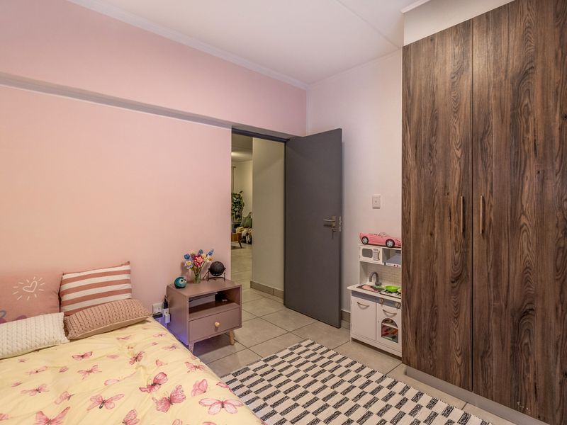 A well-maintained bedroom featuring tiled flooring and a large, modern wood-grain built-in wardrobe.