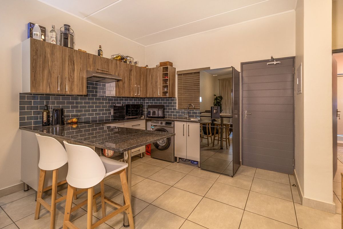 Modern kitchen featuring granite countertops, subway tile backsplash, ample built-in cabinetry, and integrated appliance space with tiled flooring.