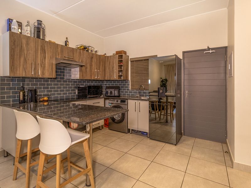 Modern kitchen featuring granite countertops, subway tile backsplash, ample built-in cabinetry, and integrated appliance space with tiled flooring.