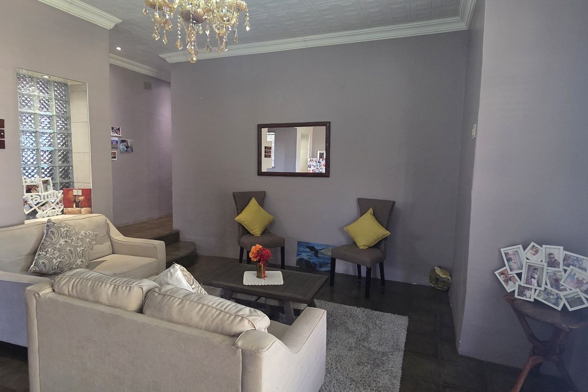 A living room featuring tiled flooring, crown molding, and a decorative glass block wall partition with integrated shelving.