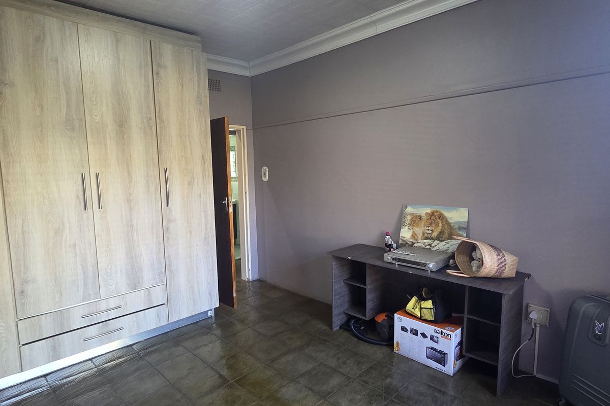 A bedroom featuring light wood-grain built-in wardrobes, tiled flooring, and neutral wall finishes, offering a functional space with ample storage.