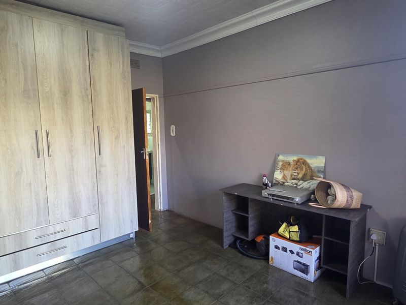 A bedroom featuring light wood-grain built-in wardrobes, tiled flooring, and neutral wall finishes, offering a functional space with ample storage.