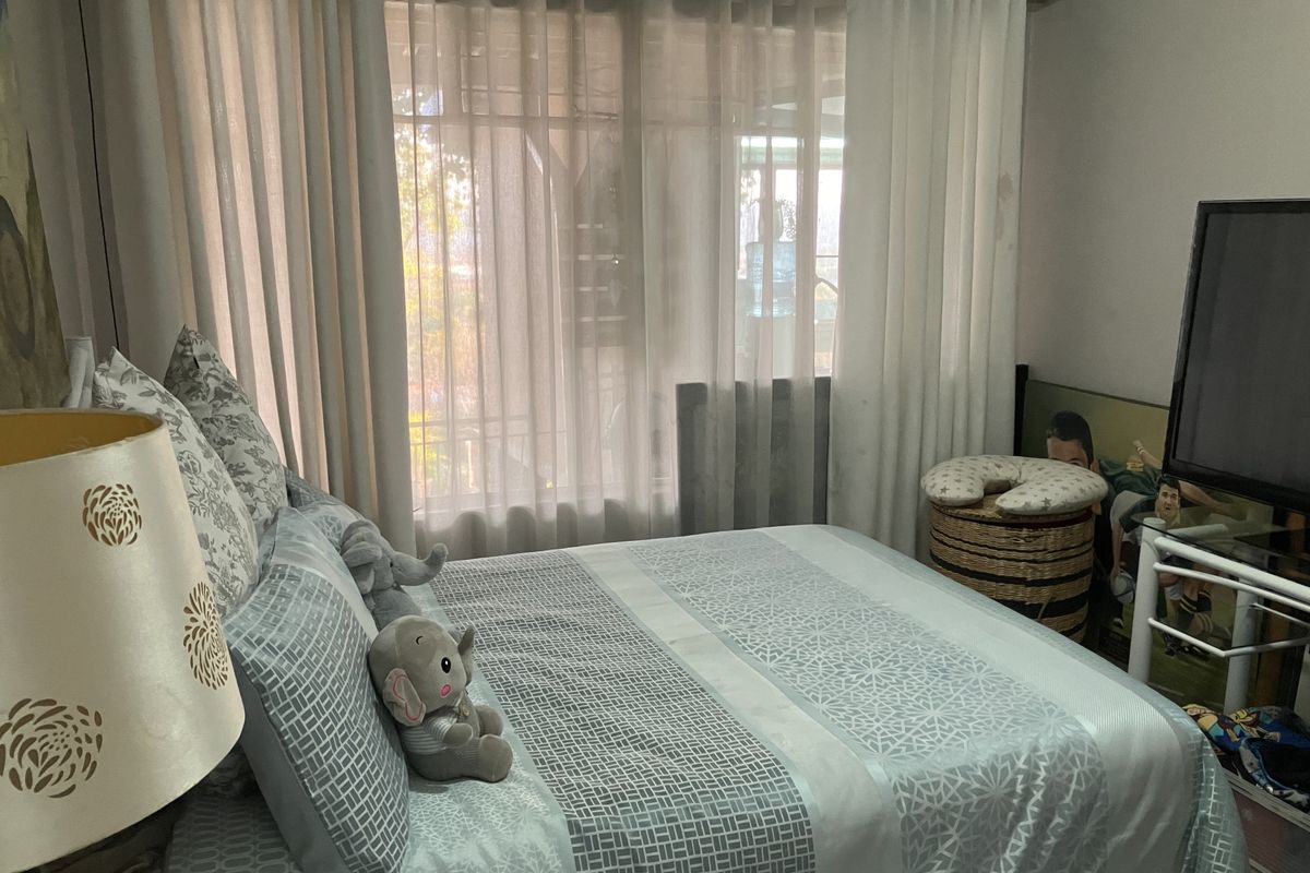 A bedroom featuring a window with installed curtain rods and sheer curtains.