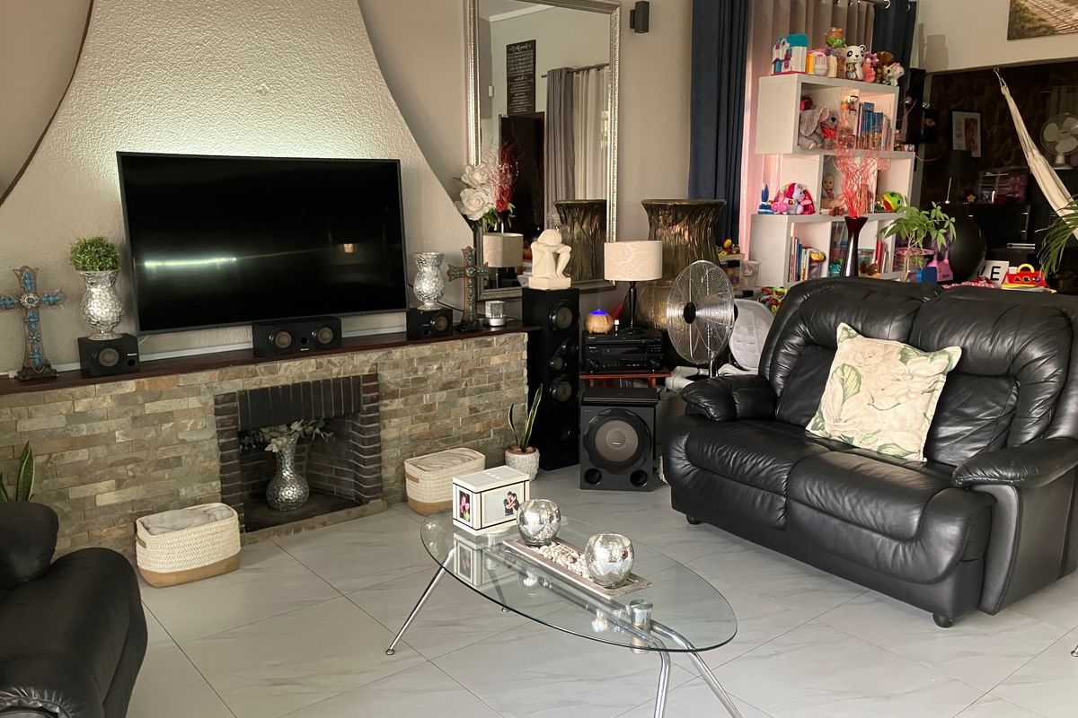A living room featuring a prominent stone-clad fireplace and tiled flooring, providing a central focal point for the home's living area.