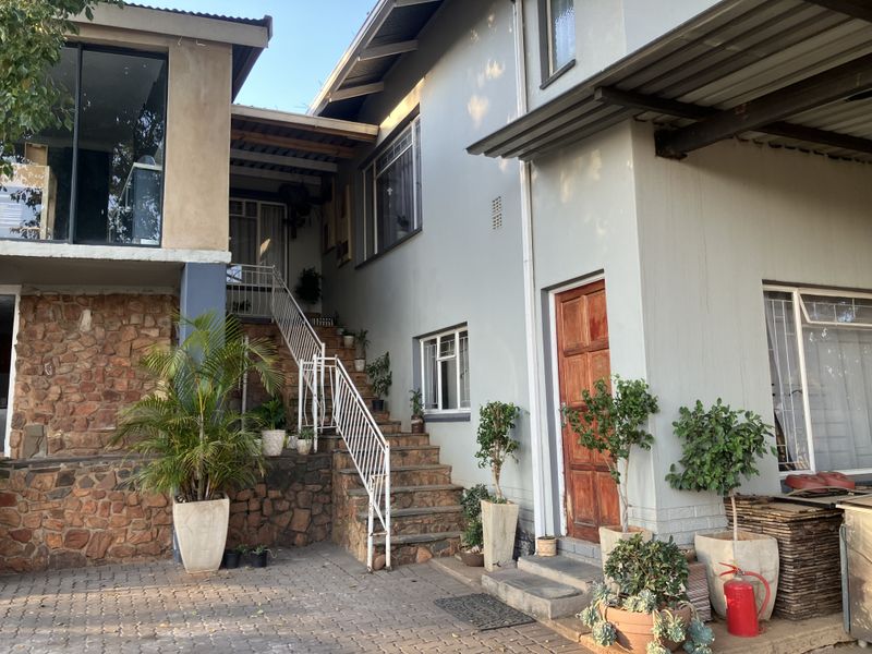 Rear exterior view of the property featuring stone cladding, a metal staircase leading to an upper level, and a paved courtyard area.