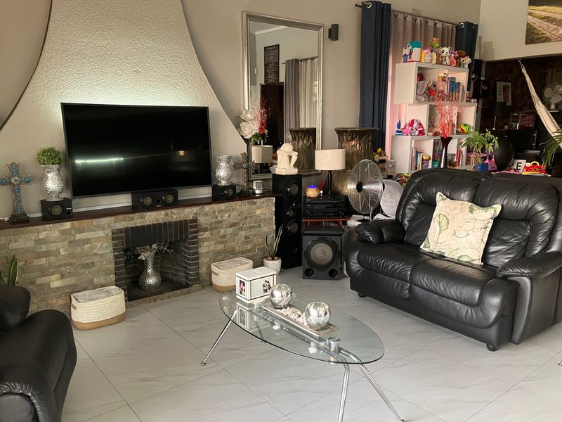 A living room featuring a prominent stone-clad fireplace and tiled flooring, providing a central focal point for the home's living area.