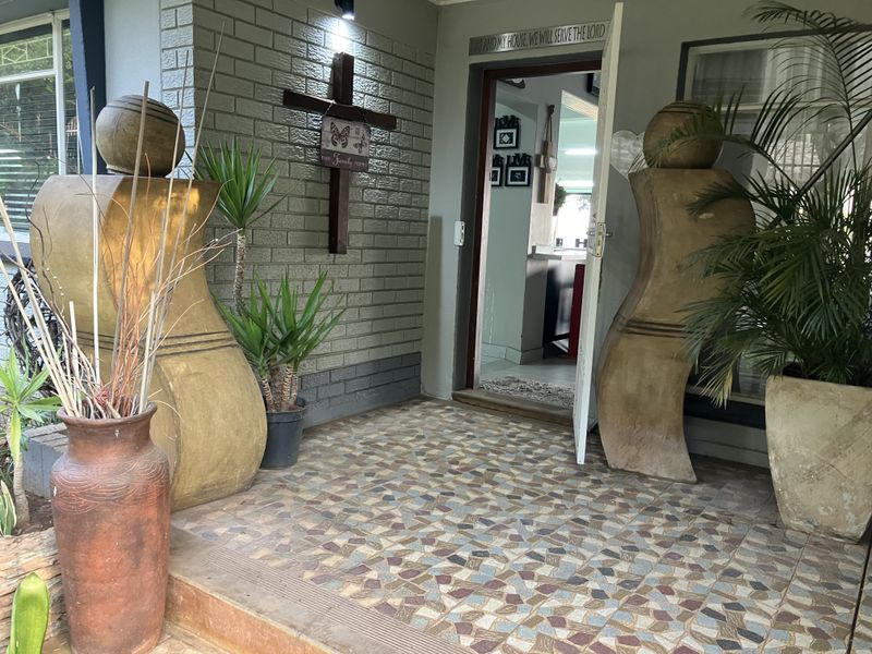 A covered front entrance featuring a brick facade and decorative tiled porch flooring, providing a welcoming access point to the home.