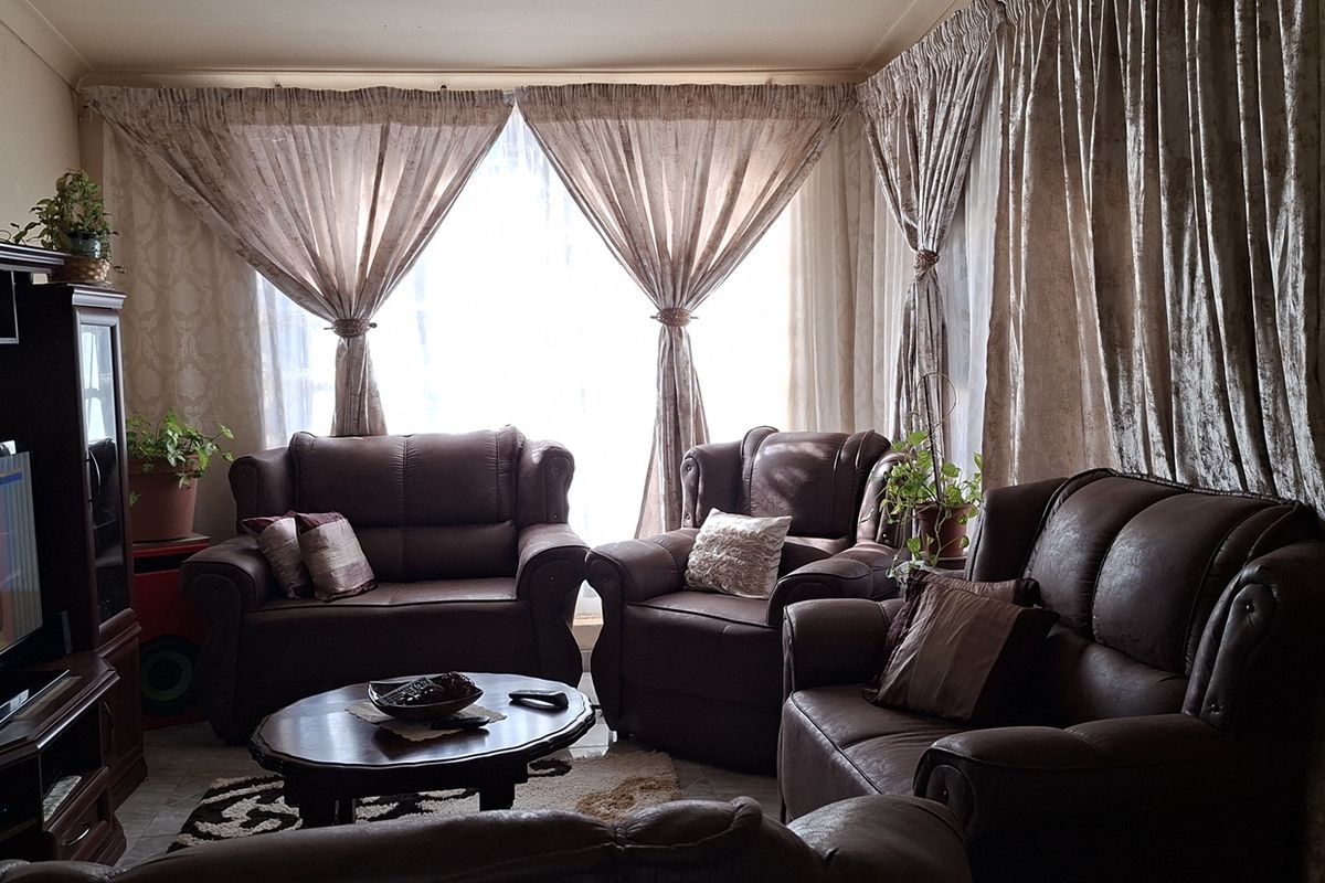 A comfortable living room featuring large windows with floor-to-ceiling curtains, providing natural light and a cozy atmosphere.
