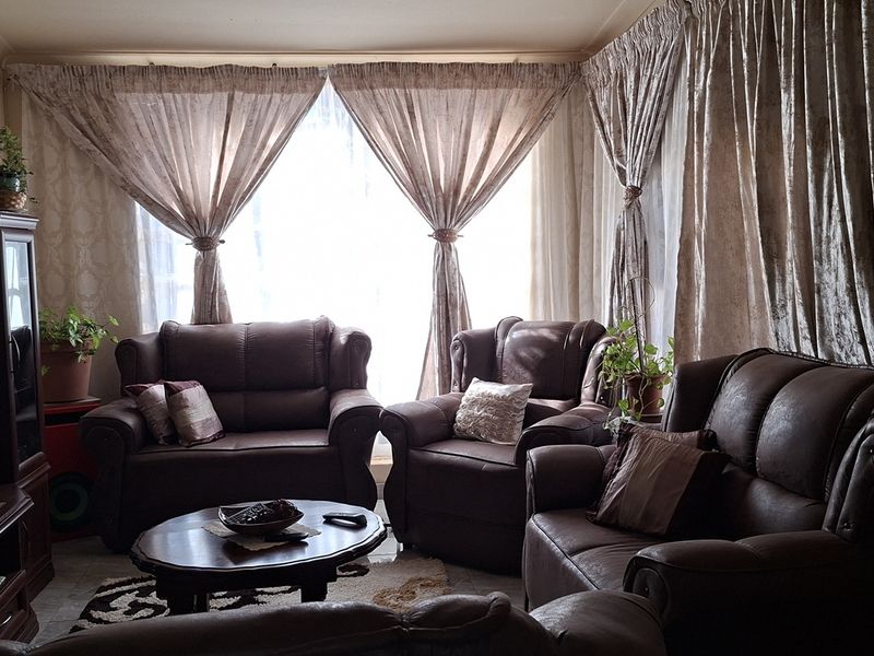 A comfortable living room featuring large windows with floor-to-ceiling curtains, providing natural light and a cozy atmosphere.