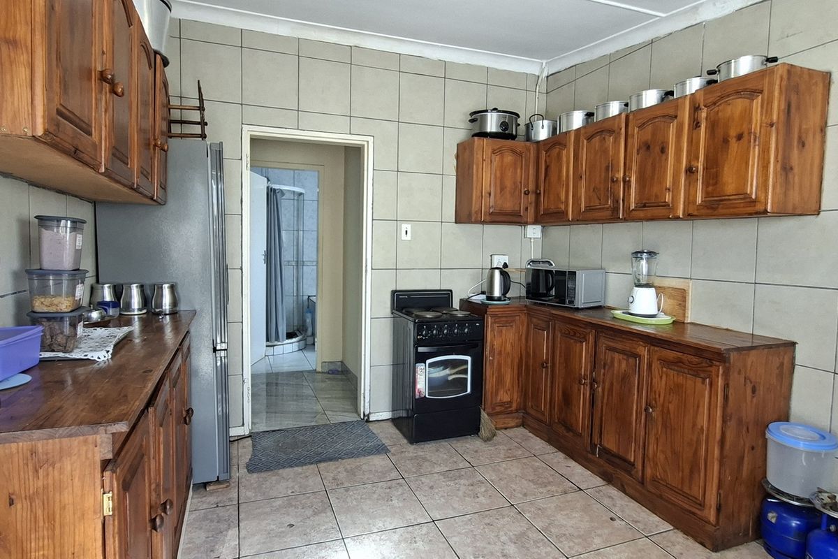 A functional kitchen featuring traditional wooden cabinetry, tiled wall splashbacks, and tiled flooring, offering a classic layout with a freestanding stove.