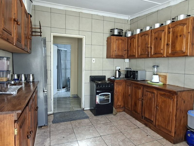 A functional kitchen featuring traditional wooden cabinetry, tiled wall splashbacks, and tiled flooring, offering a classic layout with a freestanding stove.
