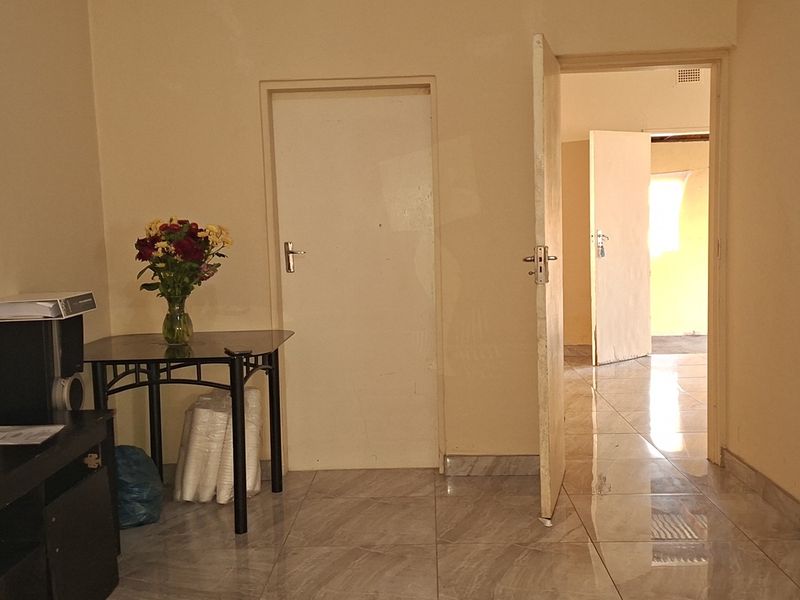 A bedroom space featuring tiled flooring and internal access doors, requiring cosmetic updates to improve the overall aesthetic and finish.