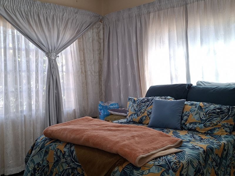 A bedroom featuring natural light through windows fitted with security bars and curtain rails.