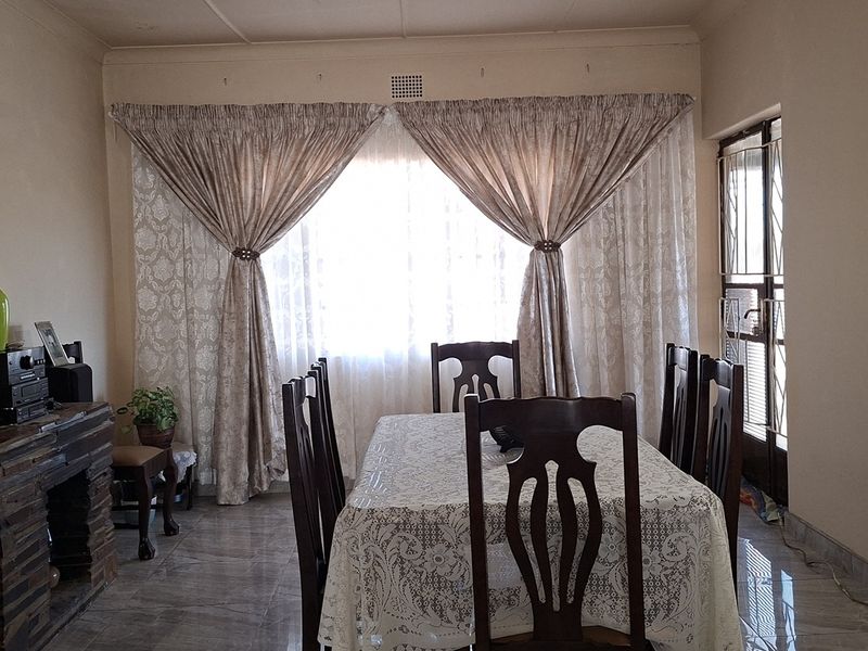 A dining room featuring tiled flooring, a built-in fireplace, and a security gate leading to the exterior.