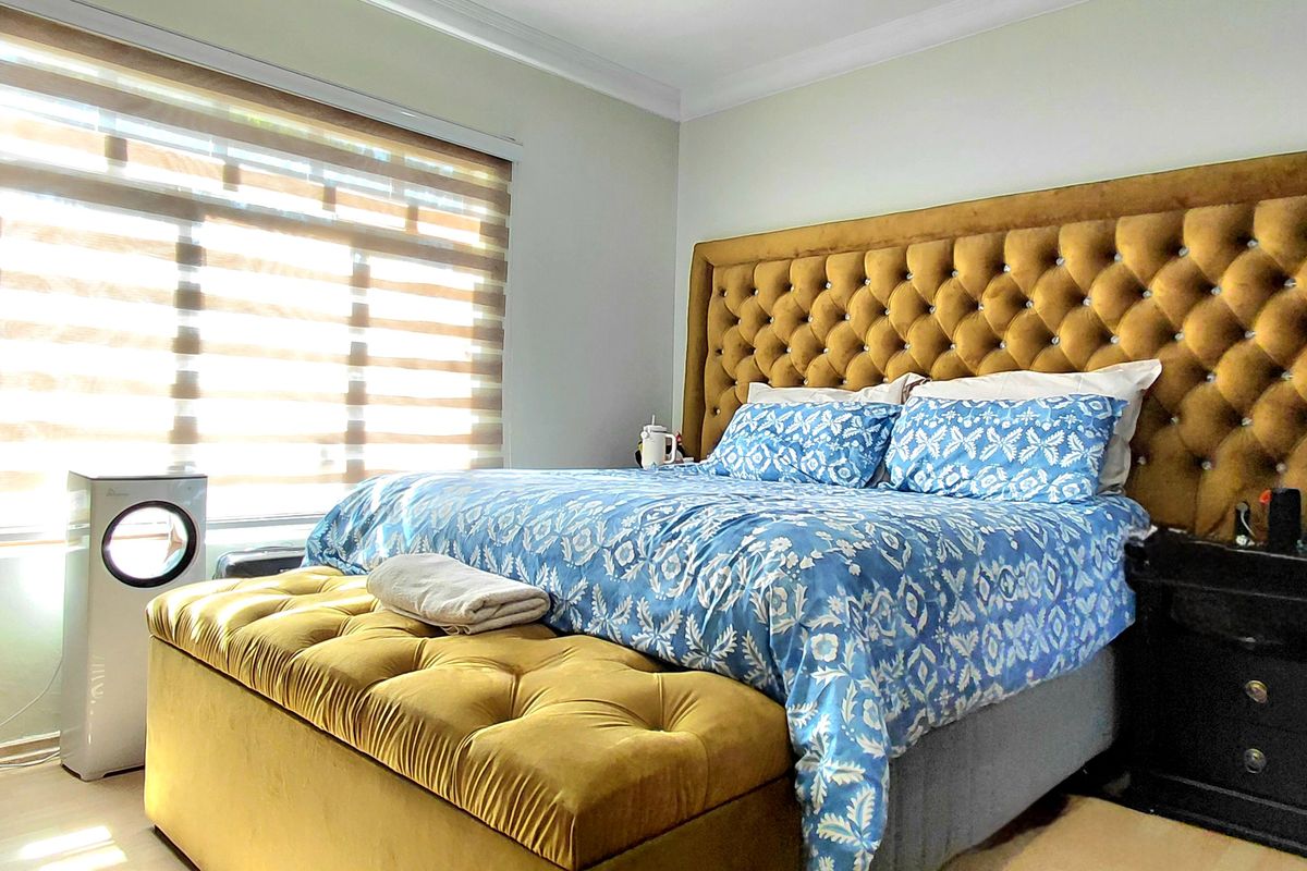 A well-maintained bedroom featuring laminate flooring, a built-in wardrobe, and modern roller blinds, providing a comfortable and functional living space.