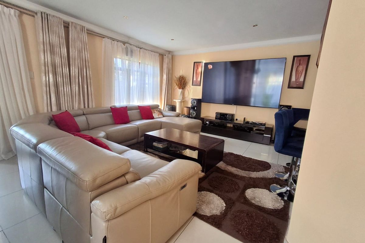 A spacious living room featuring tiled flooring and recessed ceiling lighting, providing a comfortable and well-lit area for relaxation.