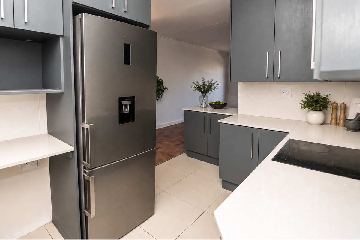 Modern kitchen featuring dark grey cabinetry, light quartz countertops, integrated induction hob, and sleek tiled flooring in a well-maintained apartment setting.