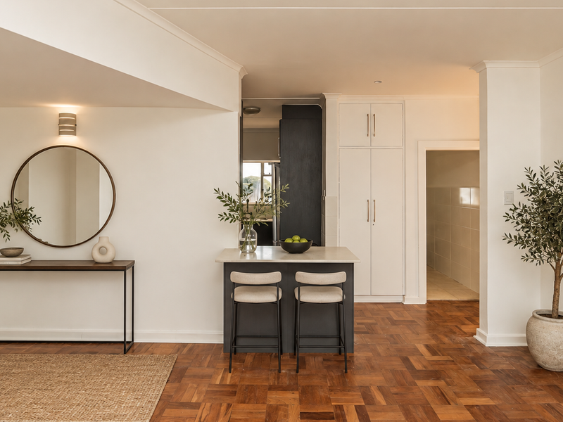 An open-plan living area featuring classic parquet flooring, a modern kitchen island with stone countertop, and ample built-in storage cabinetry.