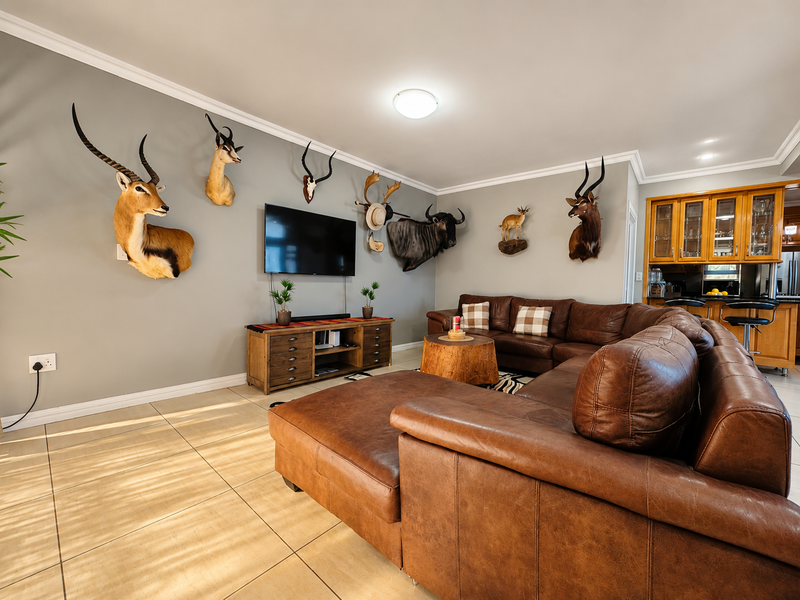 Spacious open-plan living area featuring tiled floors, crown molding, and a seamless transition into a functional kitchen with built-in cabinetry and breakfast bar.