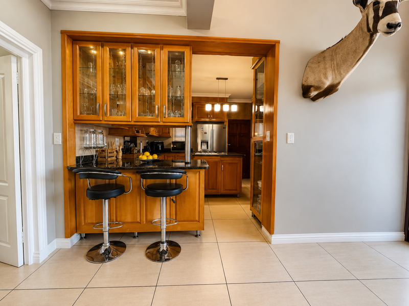 A functional scullery area featuring built-in wooden cabinetry, granite countertops, and glass-fronted display units, providing additional storage and prep space adjacent to the kitchen.