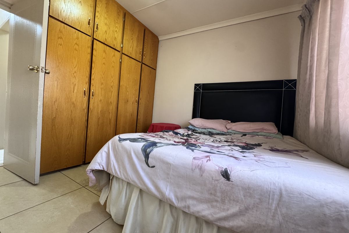A bedroom featuring built-in wooden cupboards and tiled flooring, offering a functional space with potential for modern updates.