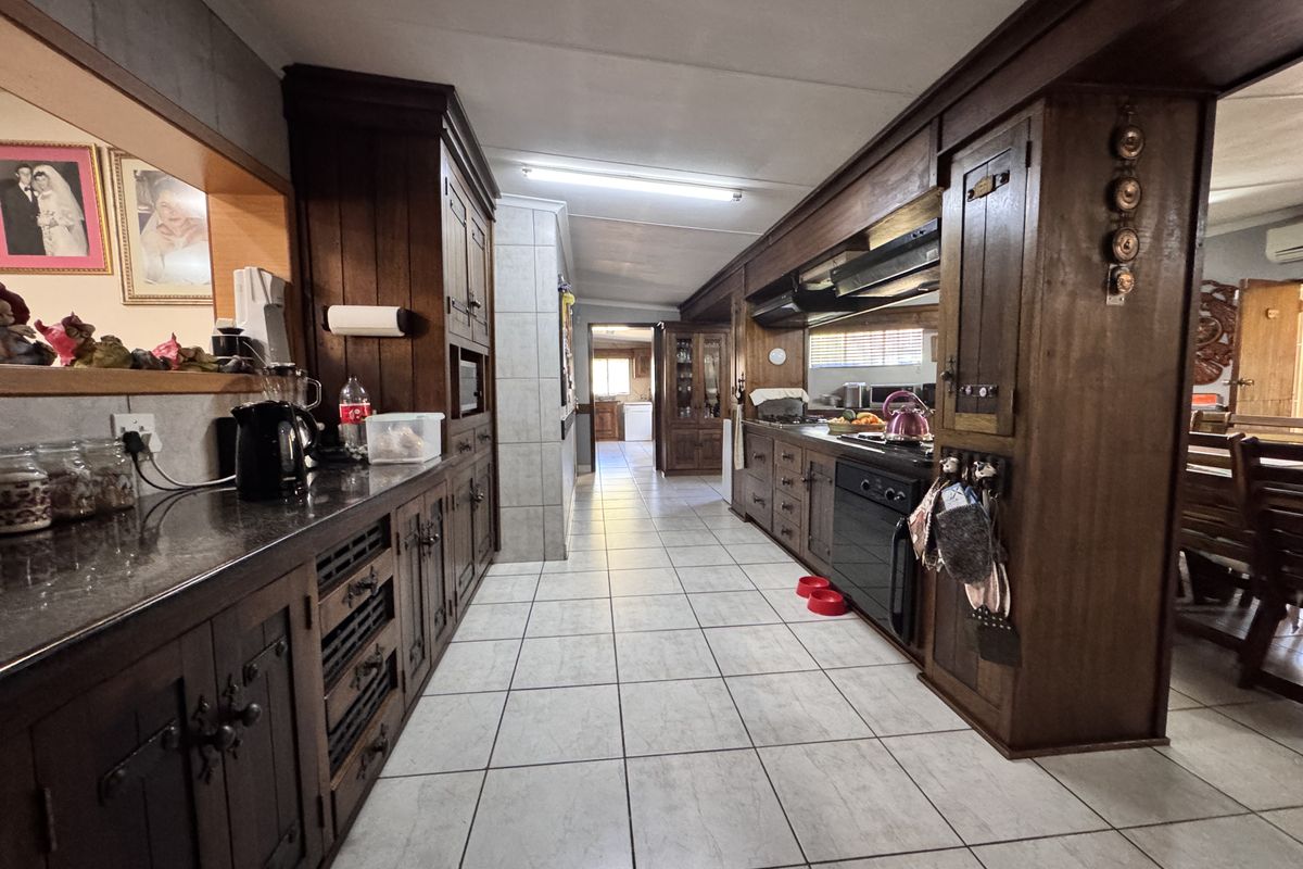 Spacious kitchen featuring extensive built-in wooden cabinetry, granite countertops, and integrated appliances, finished with neutral ceramic floor tiles.