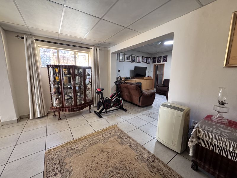 Open plan living area featuring tiled flooring and a drop ceiling, connecting two distinct lounge spaces with built-in cabinetry.