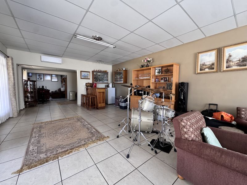 Spacious open-plan living area featuring tiled flooring, a suspended ceiling, an air conditioning unit, and a built-in bar counter.